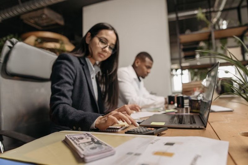Financial professionals working with a laptop, calculator and cash